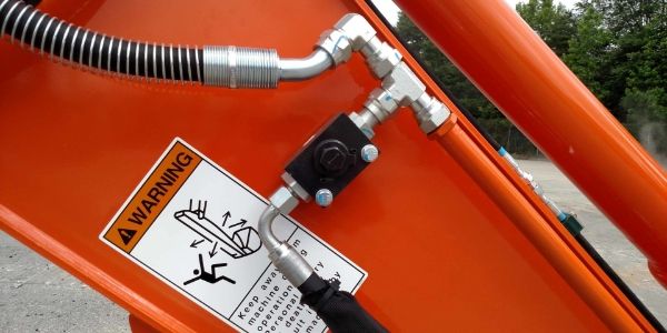 El adaptador de T de manguera está conectando dos mangueras hidráulicas y un puerto.